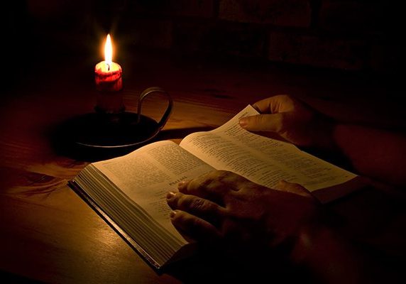 Reading the bible by candle light. Only light in this image is from the candle. Perfect for religious, eater or christmas themes.